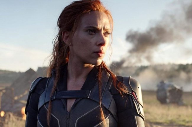 Foto da atriz Scarlett Johansson como Viúva Negra durante filme. Nela, Scarlett aparece olhando para o horizonte em um campo com fumaça preta.