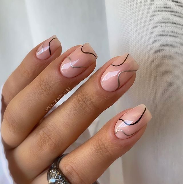 Foto com destaque nos dedos com as unhas com traços preto.