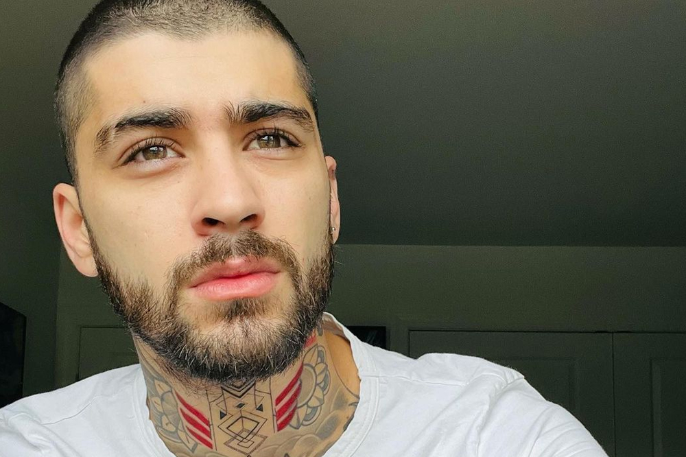 Selfie de Zayn; ele está olhando para frente e usa uma camisa branca de manga curta; a expressão é séria