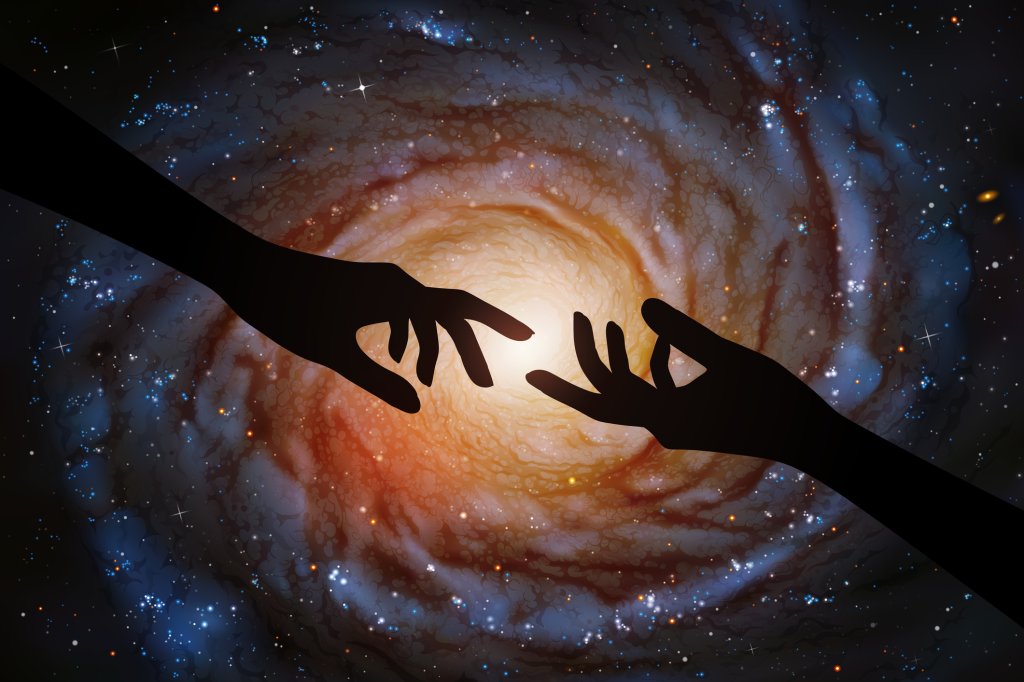 Foto de duas mãos tentando se tocar em meio à infinitude do espaço sideral