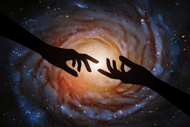 Foto de duas mãos tentando se tocar em meio à infinitude do espaço sideral