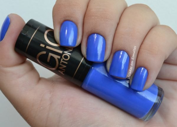Foto de uma mão segurando um vidro de esmalte da azul com as unhas azuis.