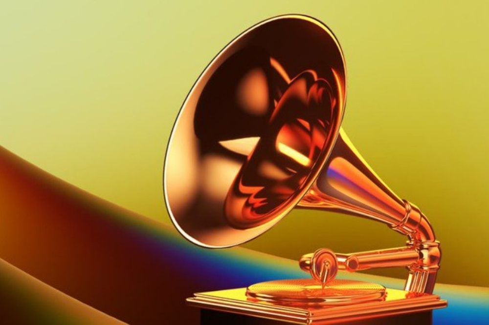 Foto do prêmio Grammy - dourado e em formato de vitrola. Ao fundo, luzes amarelas.