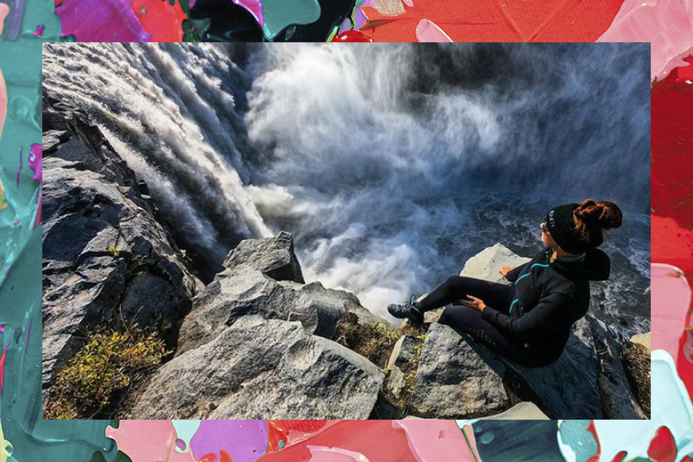 Foto da influenciadora em cima de um penhasco Zoë Snoeks. Abaixo dela, cataratas