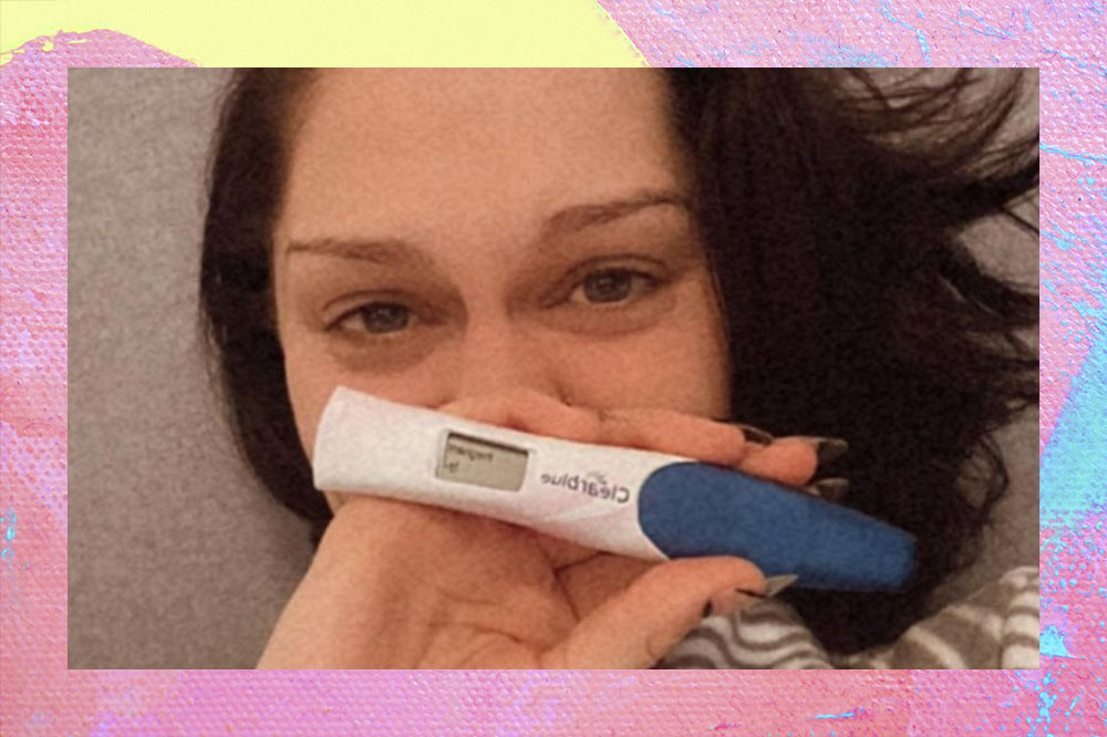 Foto de Jessie J com um teste positivo de gravidez na mão, sem maquiagem, olhos inchados e cabelos pretos.