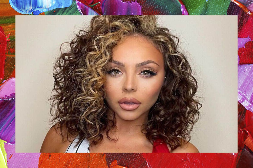 Foto de Jesy Nelson, com o cabelo cacheado e com mechas loiras, maquiagem natural.