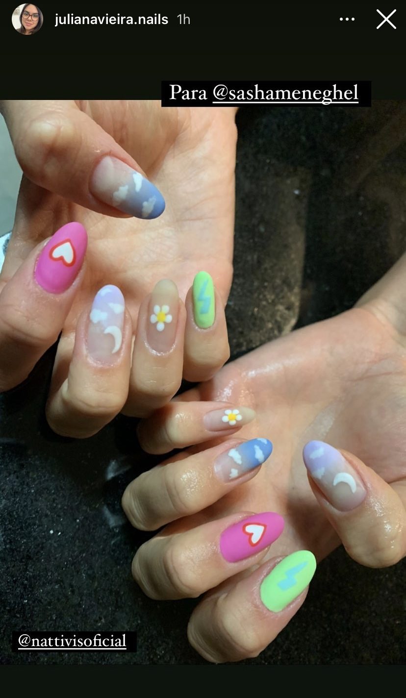 Mãos da Sasha Meneghel com nail art divertida com desenhos como coração, nuvens e florzinhas