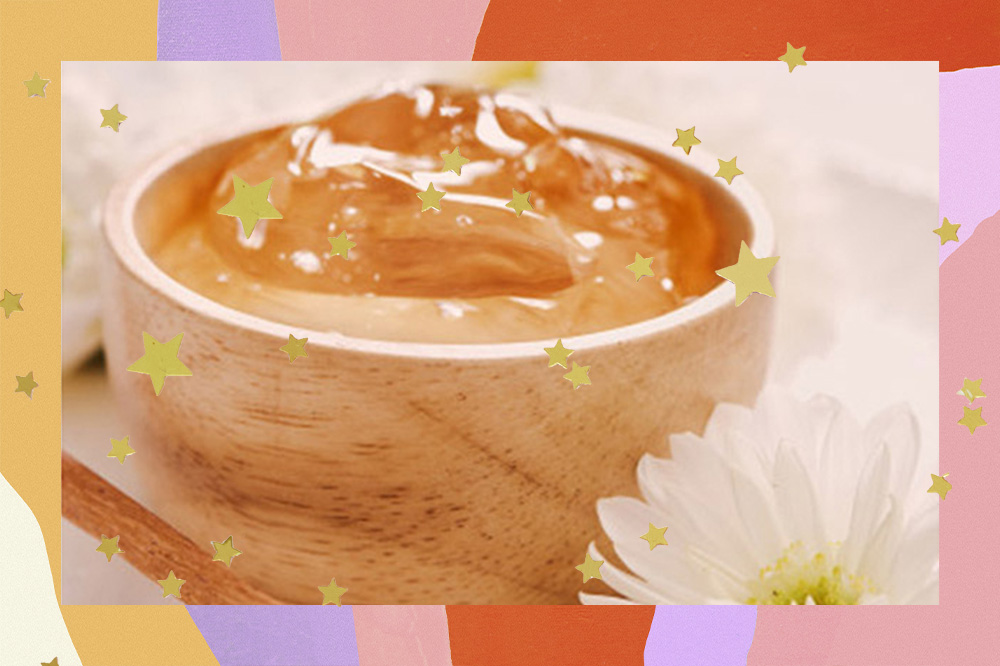 A imagem mostra fundo claro, um potinho de madeira com gelatina natural dentro e a frente uma flor branca. A montagem tem uma moldura colorida e estrelinhas douradas por toda imagem.