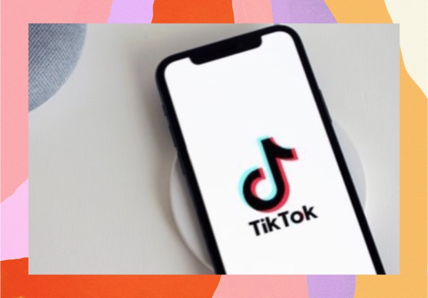 Imagem de um celular com a tela aberta no aplicativo TikTok, com moldura colorida de fundo. 