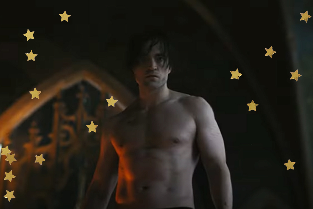 Robert Pattinson em cena do trailer de The Batman; ele está sem camisa com expressão séria olhando para câmera em um ambiente com pouca iluminação; estrelas amarelas decoram a imagem