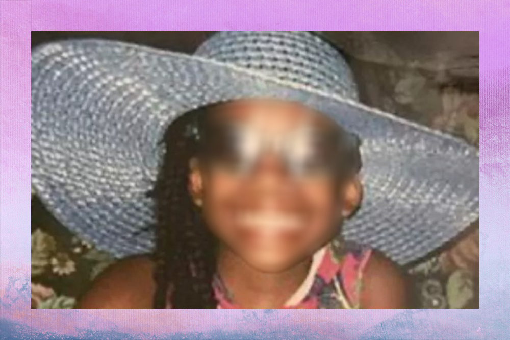 Foto de uma menina negra, de 10 anos. Ela tem o cabelo comprido, usa óculos de sol e um chapéu de praia grande e azul claro. Ela está sorrindo.