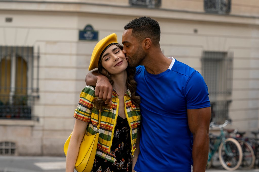 Lily Collins como Emily e Lucien Laviscount como Alfie dando beijo nela em cena da série Emily em Paris