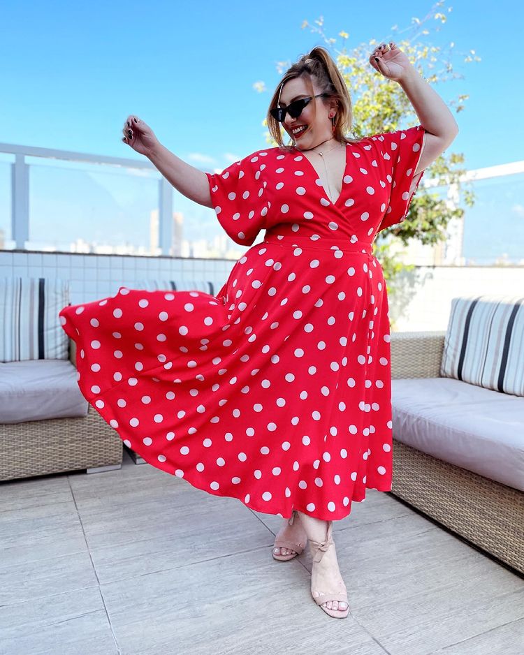 Influenciadora Ju Romano usando vestido longo vermelho de bolinhas brancas com sandália nude e óculos de sol