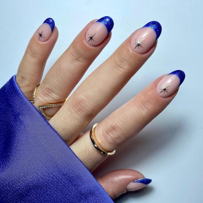 Foto de uma mão com nail art de francesinha azul com brilhos.