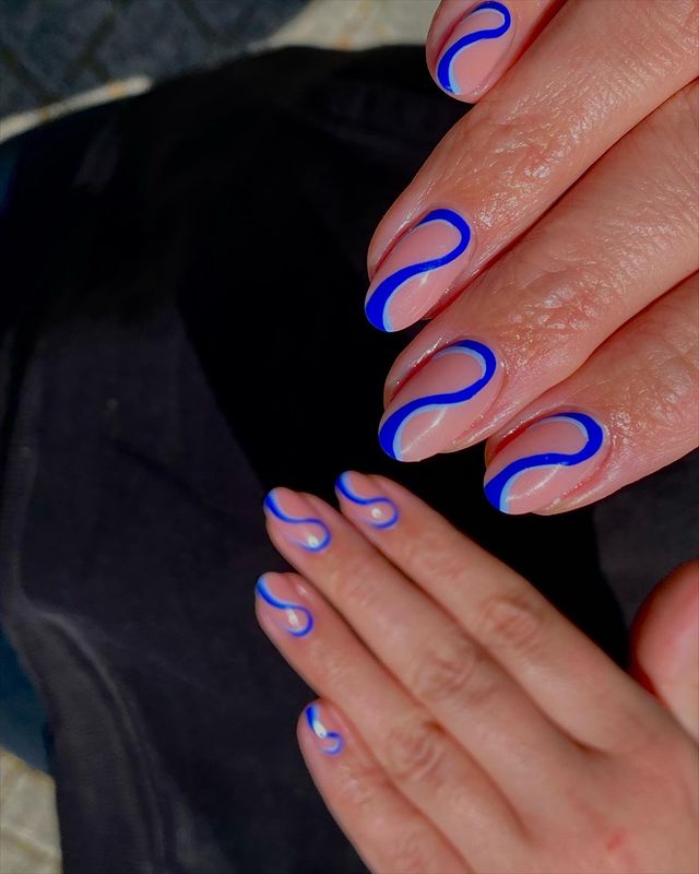 Foto de unhas da mão com decoração minimalista com ondas em tons de azul.