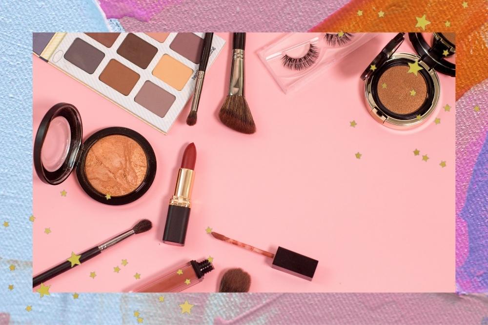Montagem com o fundo colorido e detalhes de estrelinhas douradas nas bordas com a foto de itens de maquiagem com o fundo rosa.
