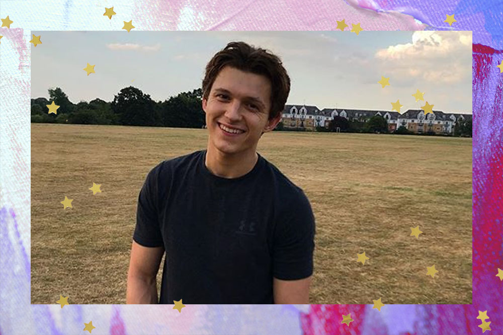 Tom com blusa preta em um campo aberto, sorrindo.