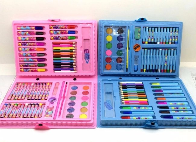 Foto de dois estojos maletas, um rosa e um azul. A maleta possui canetinhas coloridas, lápis de cor, tinta aquarela e itens de papelaria.