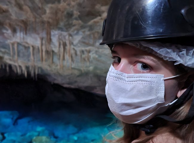 Foto da integrante da Galera, Antonela Andrade, em uma gruta com águas cristalinas, em Bonito. Antonela é branca dos olhos azulados.