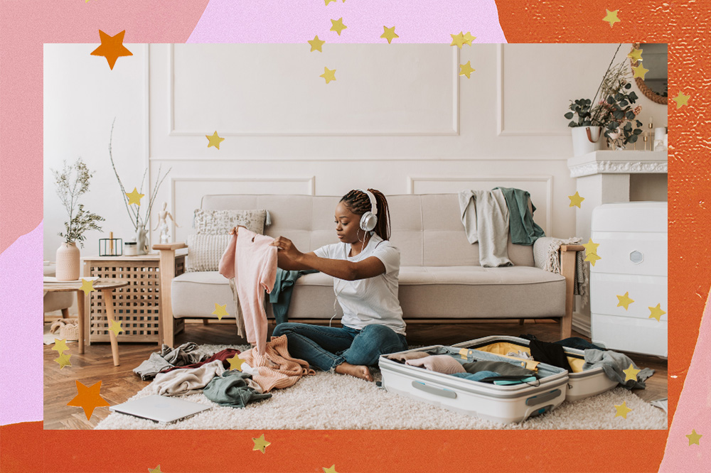 Montagem mostra, mulher negra sentada em um tapetinho branco na sala de casa, ouvindo música em um fone branco e dobrando roupas para colocar em sua mala branca de viagem. Na moldura, tonalidade do rosa e do laranja aparecem acompanhadas de estrelinhas douradas.