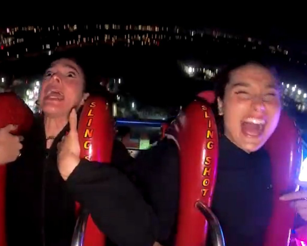 Bruna Marquezine e Sasha em brinquedo radical com assentos vermelhos; as duas estão usando roupas pretas e gritando