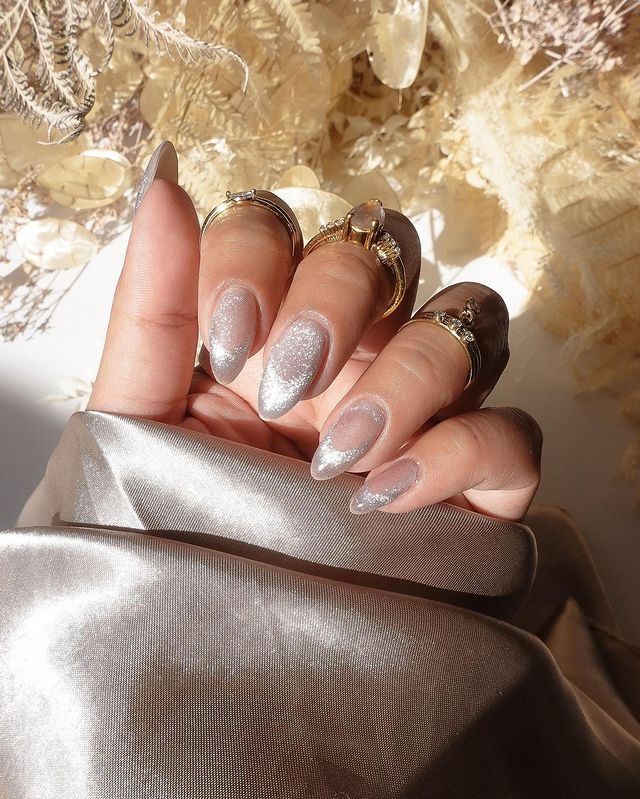 Foto de uma mão com as unhas longas e nail art com efeito aveludado com esmalte metalizado.