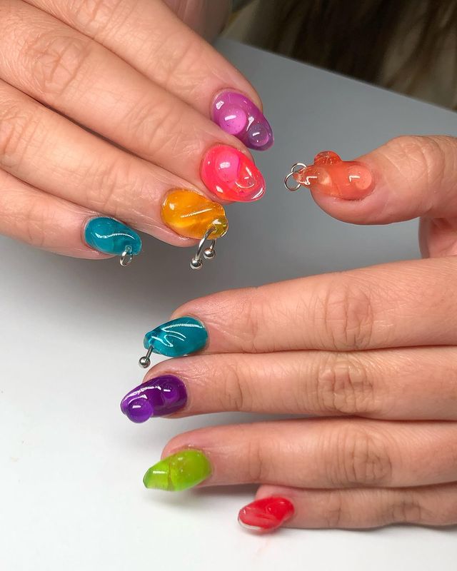 Foto de unhas coloridas com efeito jelly e detalhes em 3D.