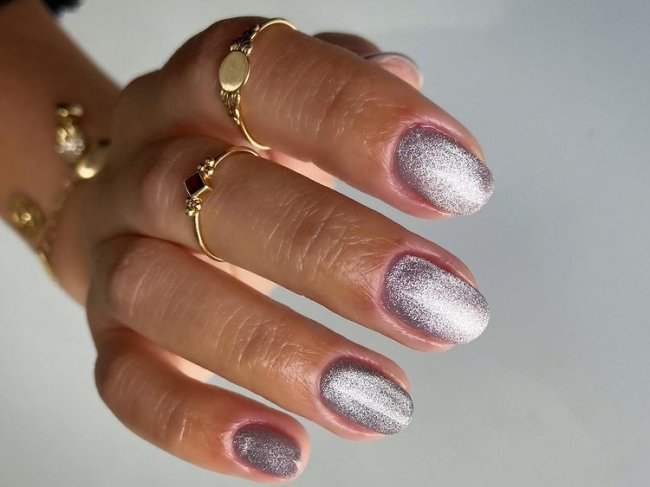 Foto de uma mão com as unhas médias com nail art aveludada com esmalte prata.