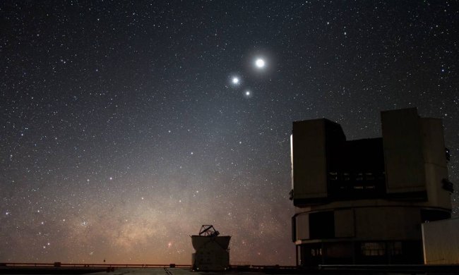 Imagem de um território amplo, ambiente escuro e com fundo de um céu estrelado. Em tons escuros, aparecem o contorno de satélites.