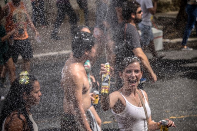 Foliões em meio a espumas e confetes durante um bloco de Carnaval em São Paulo