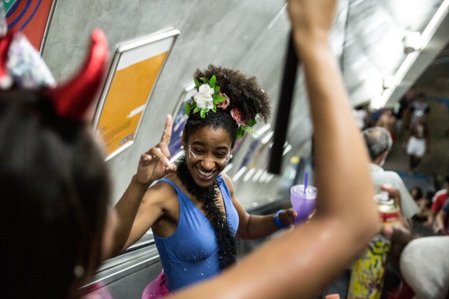 Mulheres fantasiadas no Carnaval descendo uma escada rolante do metrô em São Paulo