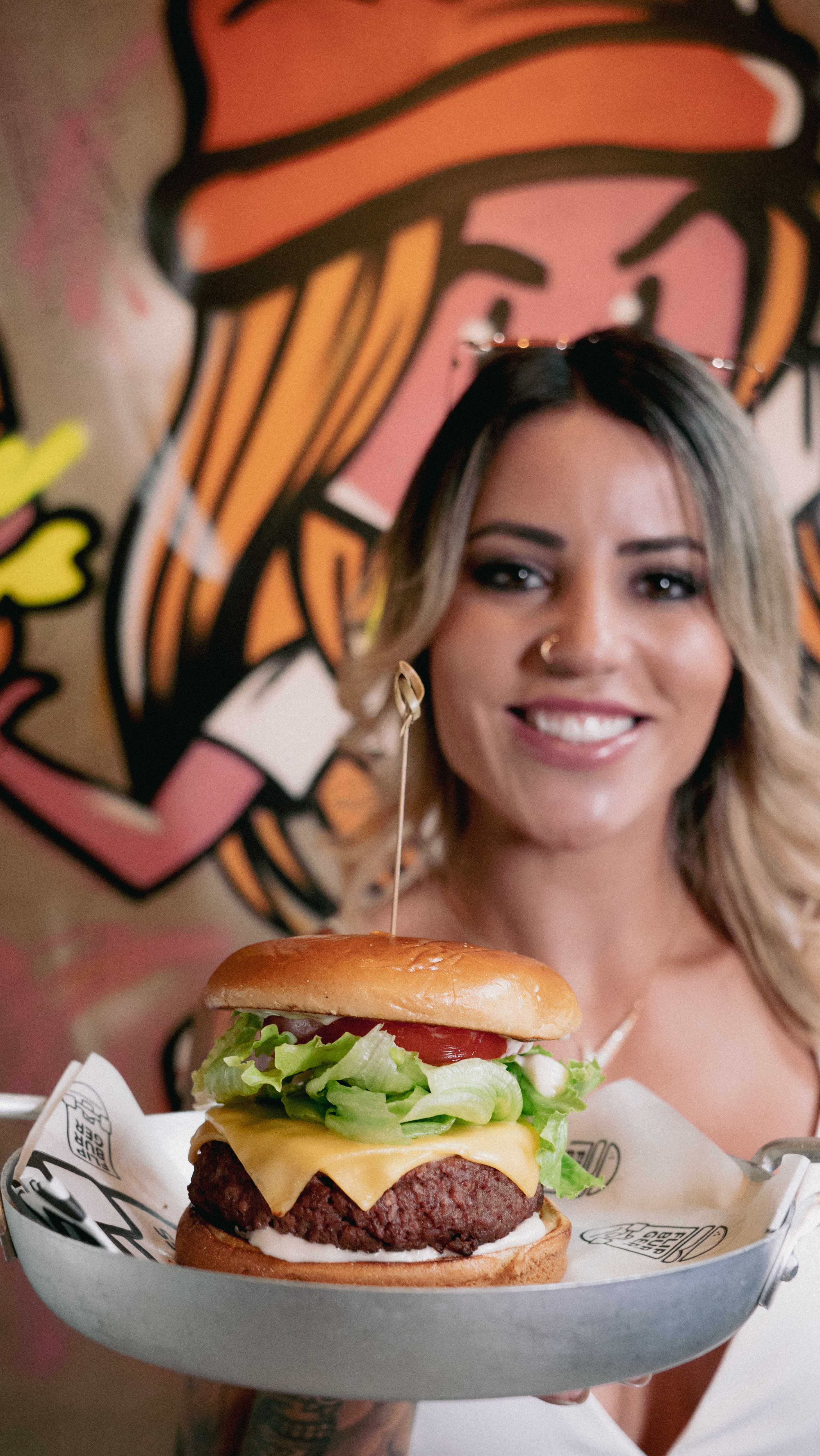 Leticia Bufoni sorrindo e segurando um hambúrguer em sua hamburgueria