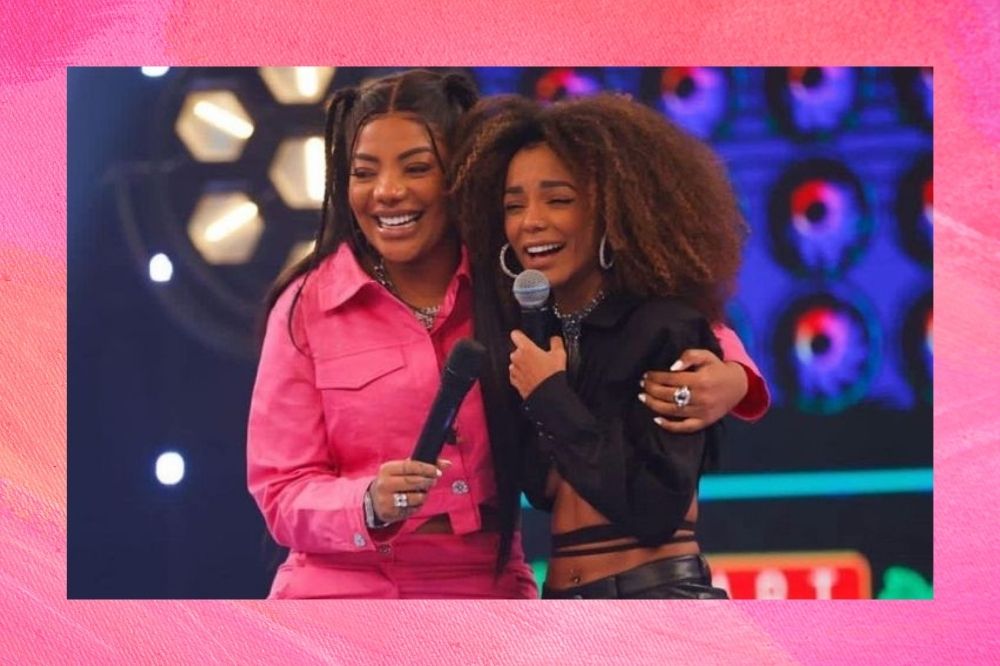 Ludmilla e Brunna Gonçalves no palco do Domingão, abraçadas e com microfones na mão.