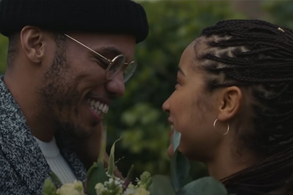 Casal sorrindo um para o outro em cena do clipe de Make It Better com flores entre eles