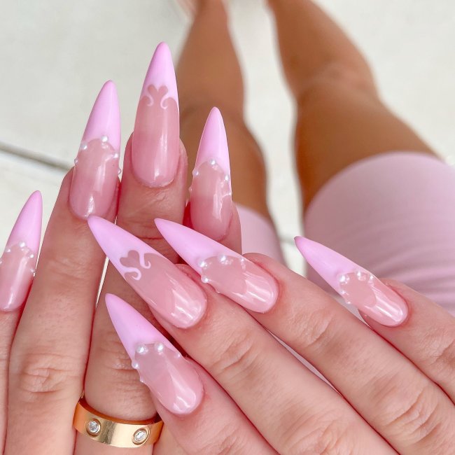 Foto de mãos com as unhas longas decoradas com uma francesinha rosa e aplicação de pérolas.