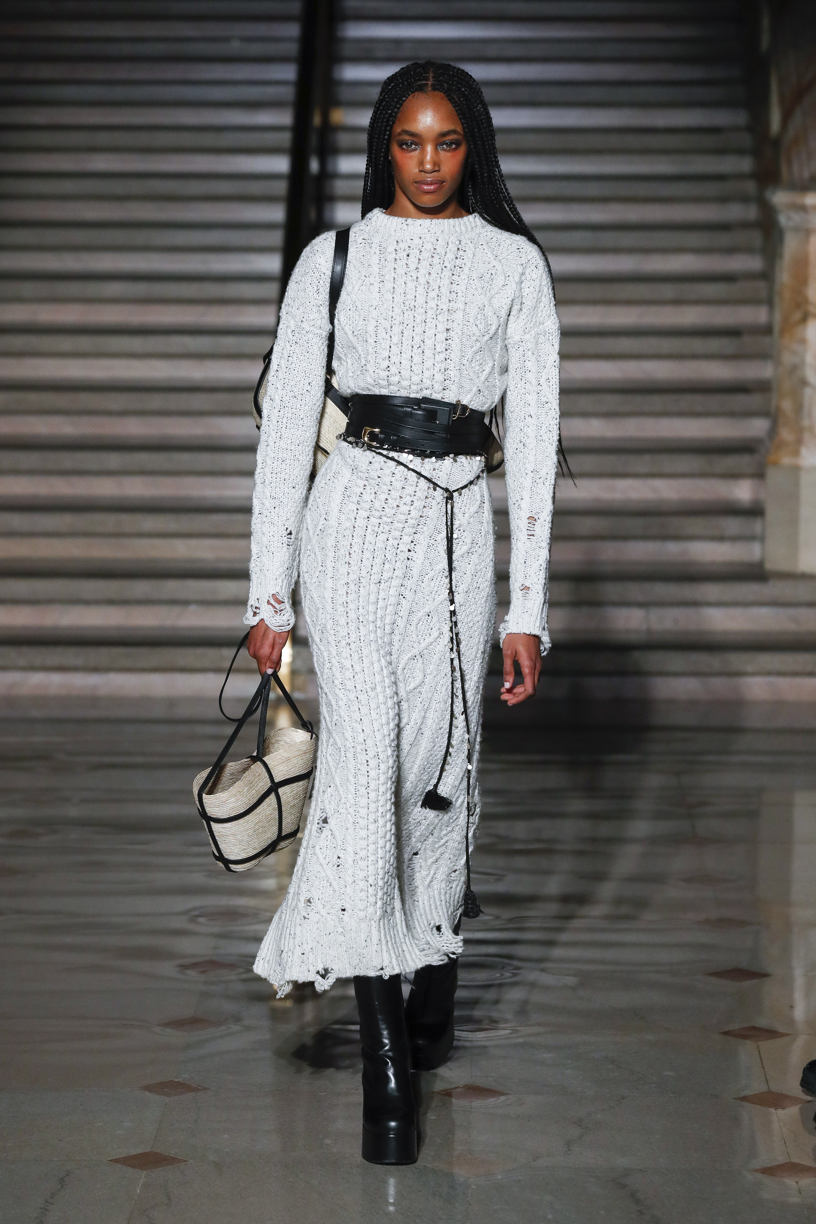 Modelo usando vestido branco de tricô longo com cinto preto e segurando uma bolsa em Desfile da Altuzarra na semana de moda de Nova York