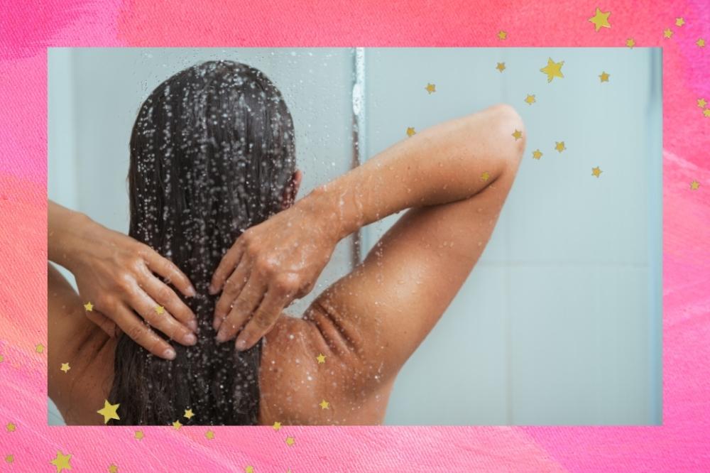 Montagem com o fundo rosa e detalhe de estrelas douradas nas bordas com a foto de uma mulher lavando o cabelo no banheiro de costas para a foto.