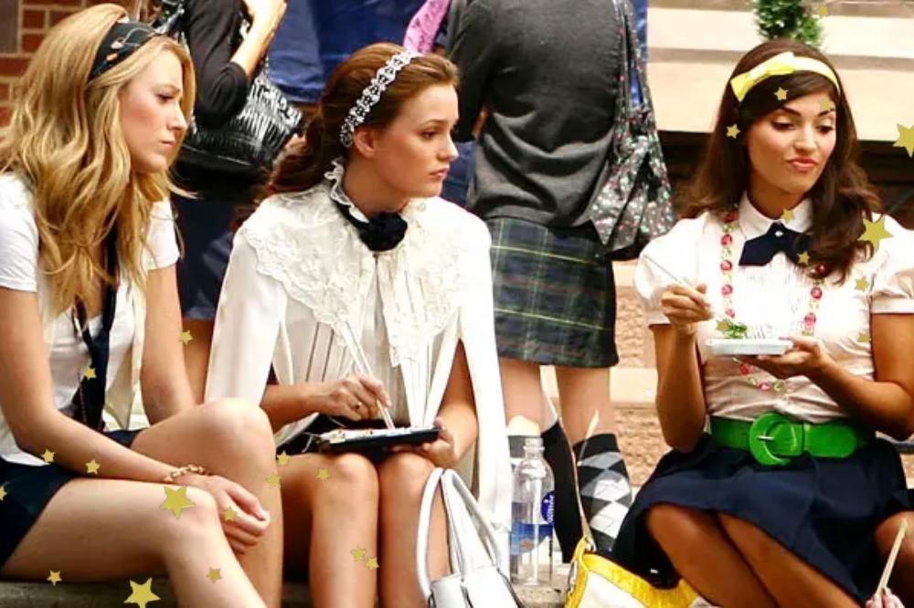 Foto de uma cena de Gossip Girl com a Serena, Blair e outra personagens sentadas em uma escada de uniforme.