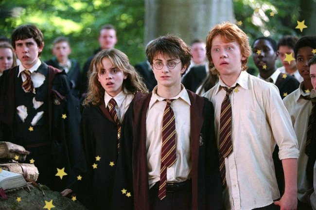 uniforme-grifinoria-harry-potter Cena de uma cena de Harry Potter com a Hermione, Harry e Rony. Os três estão lado a lado com expressões de surpresa e choque, usando uniformes da Grifinória.