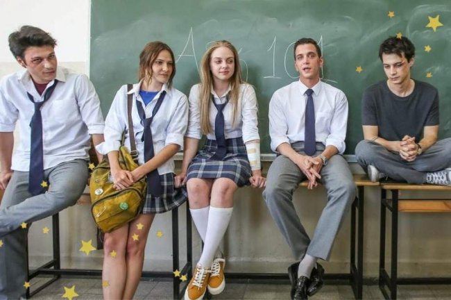 Protagonistas de Love 101 em cena da série sentados nas mesas na sala de aula com uniformes.