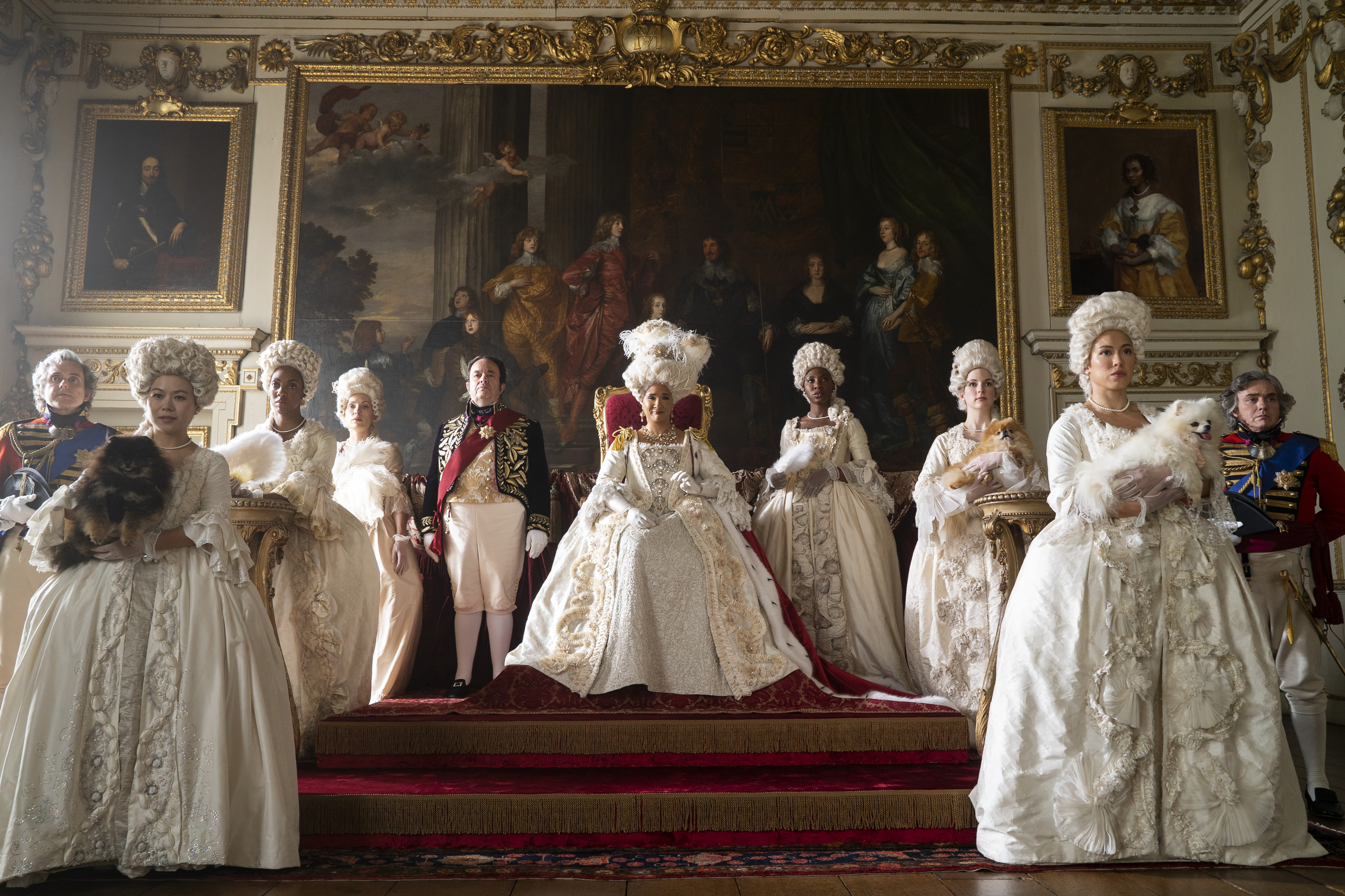 Imagem mostra, da esquerda para a direita, Hugh Sachs como Brimsley, Golda Rosheuvel como Rainha Charlotte e outros membros em cena no palácio de Char no primeiro episódio 2ª temporada de Bridgerton.