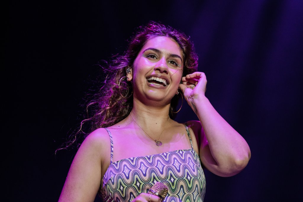 Alessia Cara sorrindo no palco do Lollapalooza Brasil enquanto olha para o público e arruma seu retorno de som no ouvido