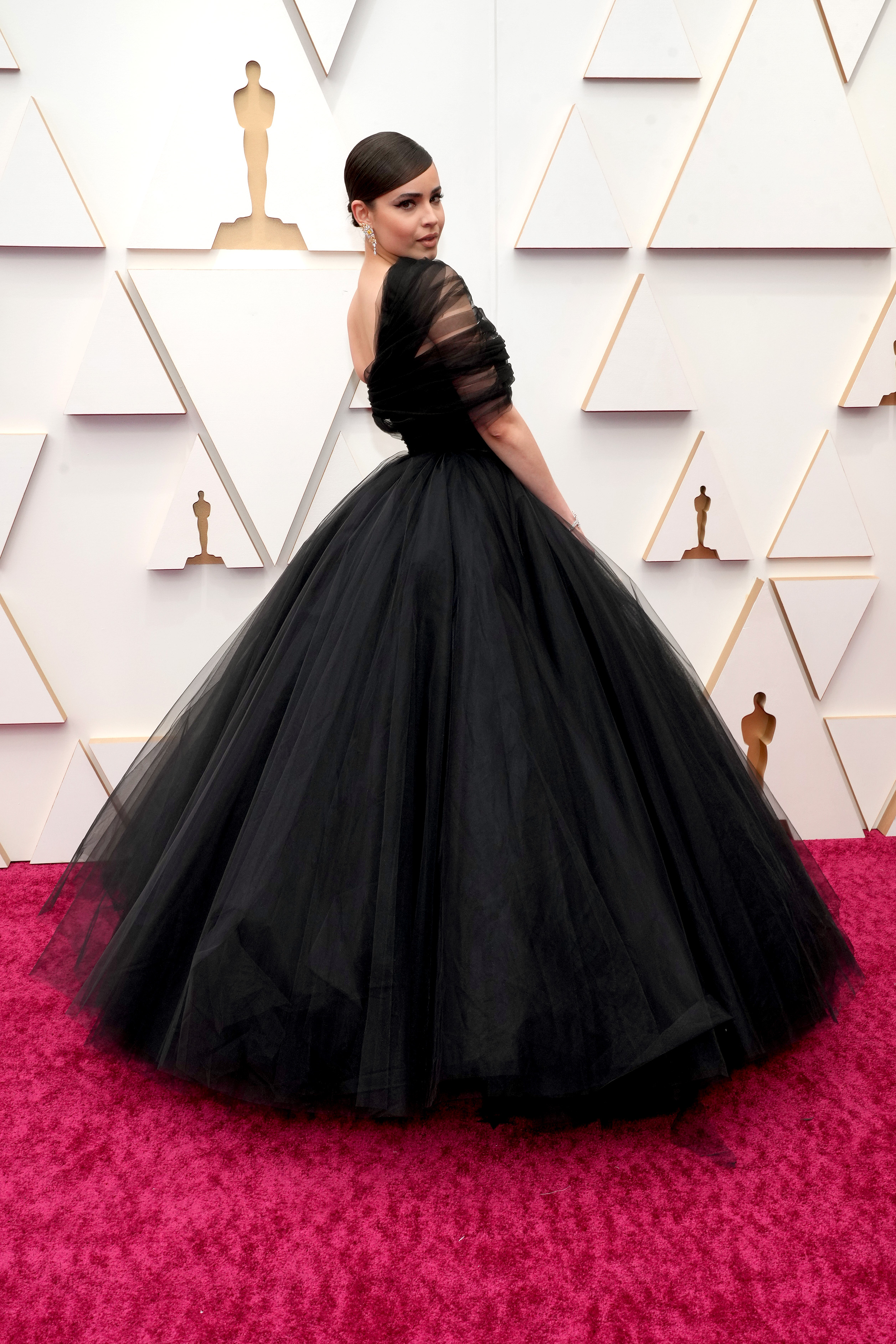 Sofia Carson usando vestido preto volumoso no tapete vermelho do Oscar 2022