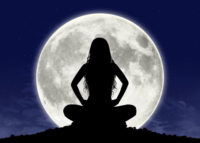 Silhueta de uma mulher de cabelos compridos meditando sobre uma enorme lua cheia