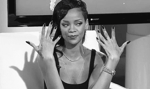 Gif em preto e branco mostra Rihanna sacudindo e exibindo suas unhas. Ela usa jóias e uma regata preta.