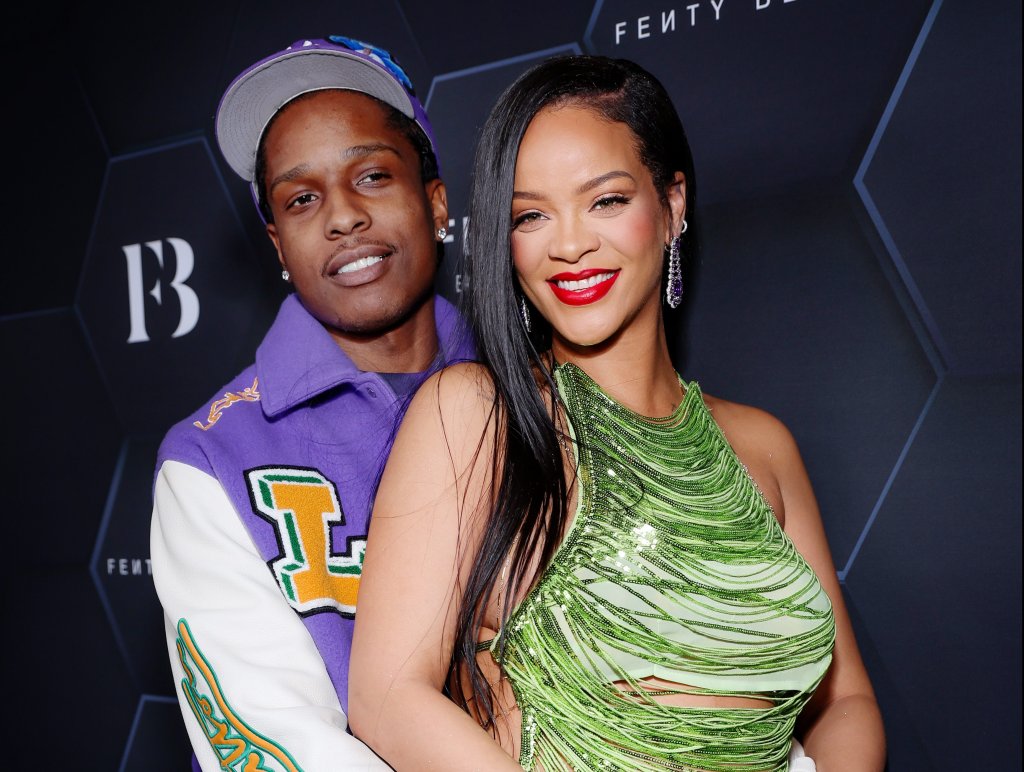 A$AP Rocky e Rihanna em evento da Fenty Beauty; ele está abraçando a cantora por trás e com a mão em sua barriga de grávida; Rihanna está sorrindo e usa um look na cor verde