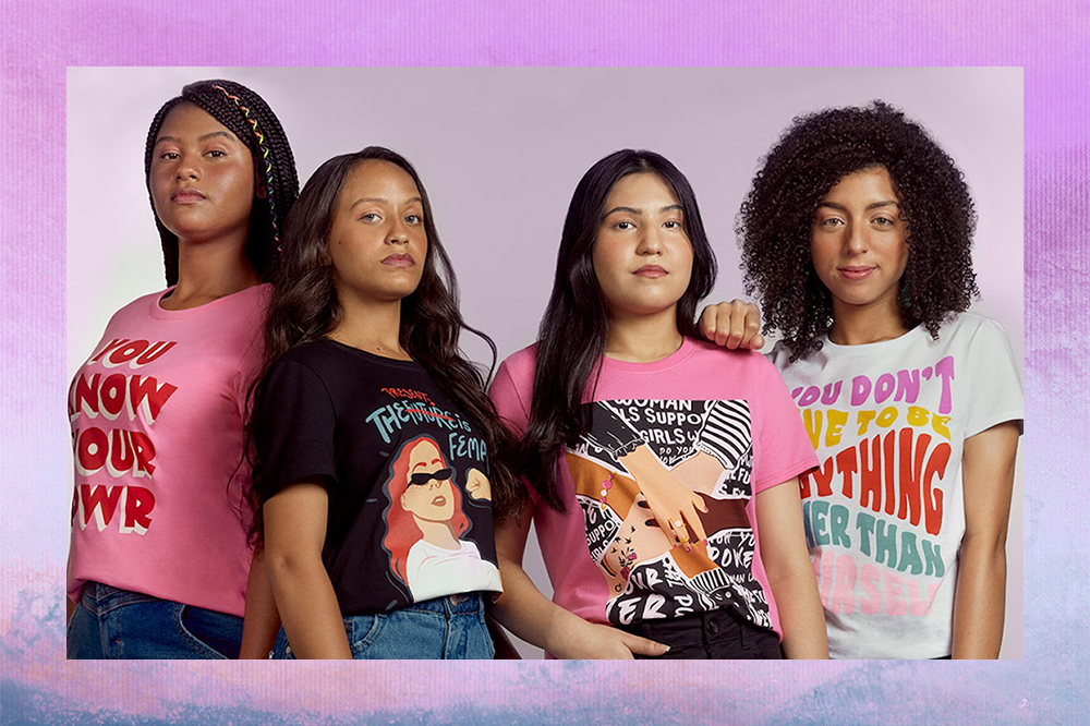 Quatro garotas olhando em direção à câmera e usando camisetas com mensagens de empoderamento feminino