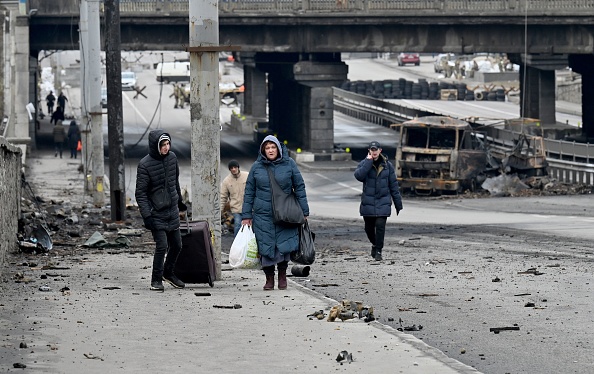 As pessoas carregam seus pertences enquanto passam pelos escombros do combate das últimas semanas na capital ucraniana de Kiev