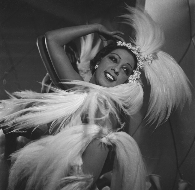 Foto em preto e branco da cantora e dançarina Josephine Baker com uma fantasia de plumas em 1926.