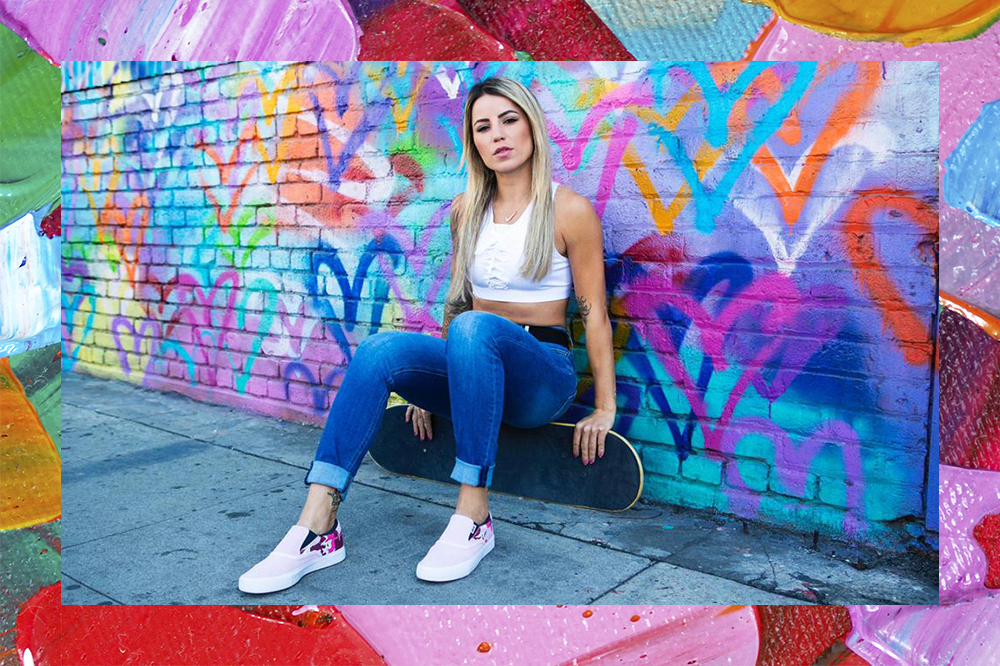 Montagem de foto de Leticia Bufoni em fundo colorido. Ela está sentada em cima de um skate usando top cropped branco, calça jeans e seu tênis da Nike, o fundo da parede atrás está cheio de corações coloridos